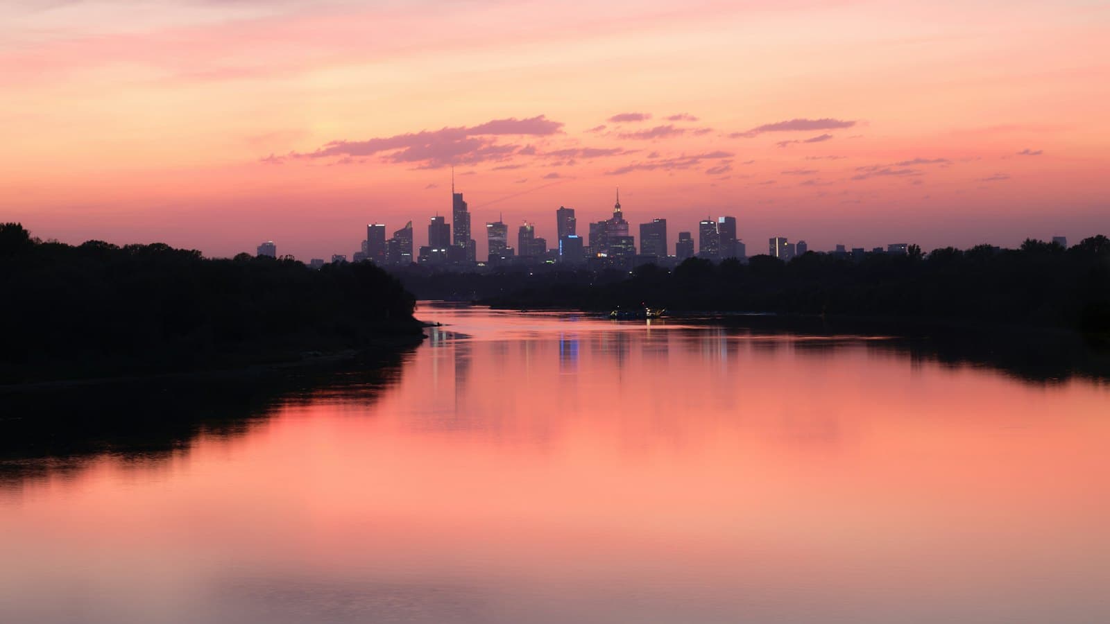 The Warsaw skyline at pink sunset reflected in the Vistula River